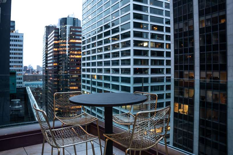 Highwater Rooftop outdoor patio seating area with metal chairs and Manhattan skyscraper views